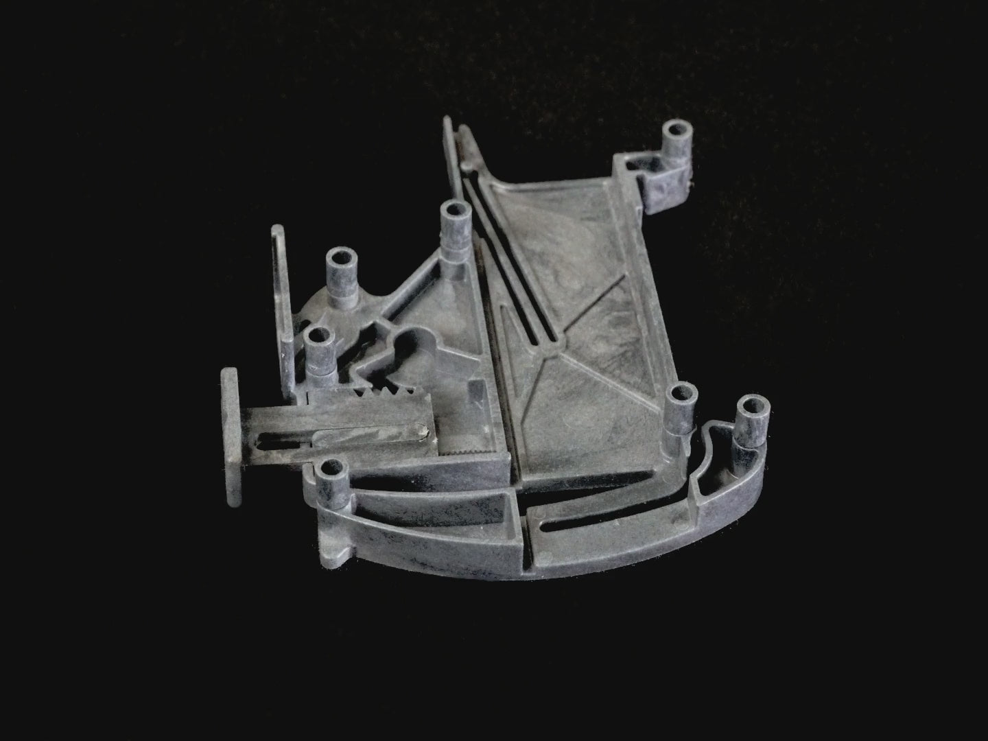 Removing an extension pin from an MTI housing half: the housing lies flat and one finger presses it down beside each pin as it is pulled off