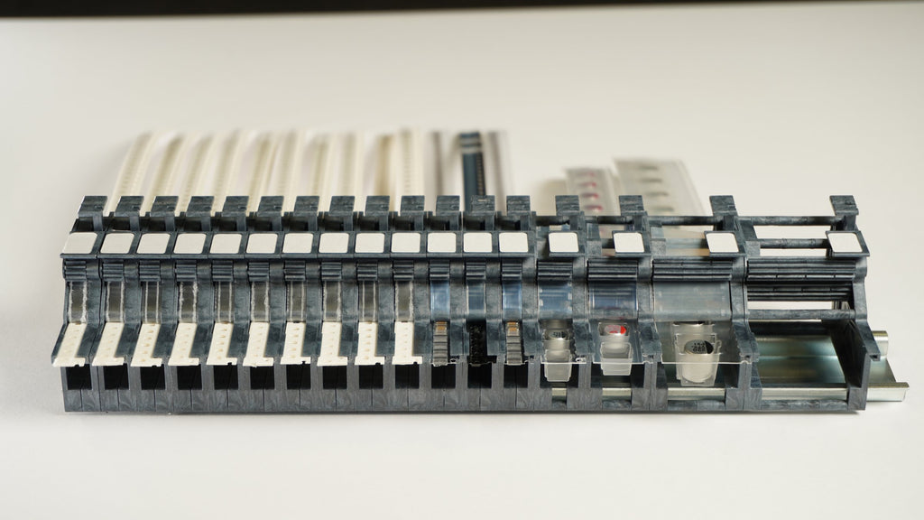 Front view of an MTI feeder bank on DIN rail showing pick points in a row, each feeder 2 mm wider than its tape