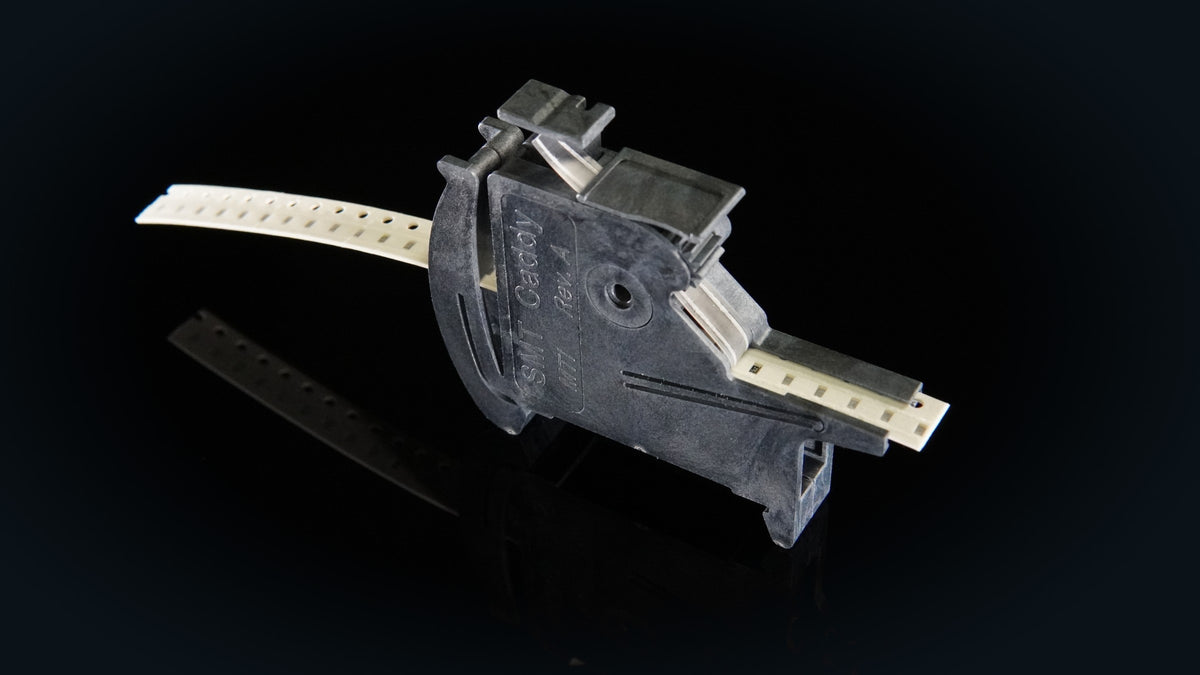 SMT Caddy MTI tape feeder loaded with 8 mm paper tape, on a dark reflective surface