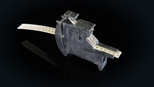 SMT Caddy MTI tape feeder loaded with 8 mm paper tape, on a dark reflective surface